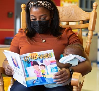 Mariah Tolson, Head Start/Early Head Start teacher, reads from her book, Little Hands, to a quiet audience of one.
