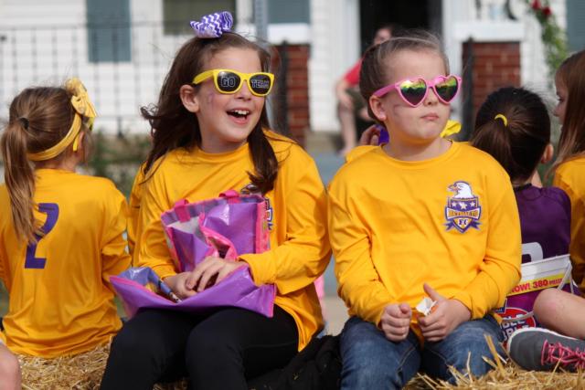 Two young members of the Bethalto Football Club throw candy to the crowds while wearing some cool shades. 