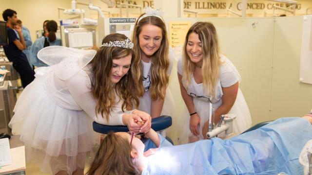 A group of tooth fairies offer encouragement to a child during the SIU SDM’s Give Kids a Smile Day.