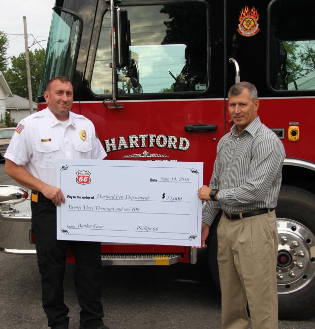 Hartford Fire Chief Bill Owens is presented a check for $23,000 to pay for new bunker gear for the Hartford Fire Fighters by Phillips 66 Terminal Supervisor Jim Mayse.