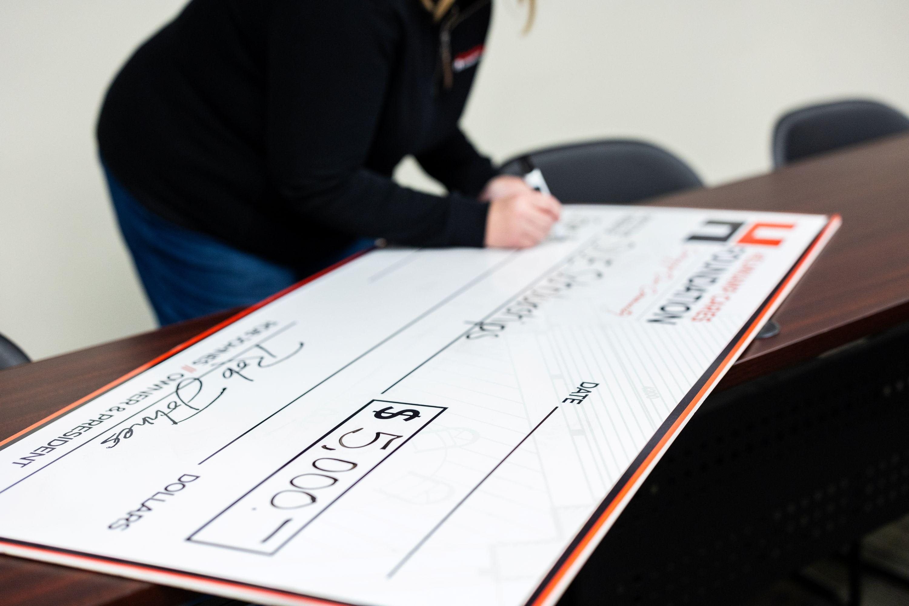 Helmkamp Cares Foundation big check filled out regularly for scholarships and maximum impact donations