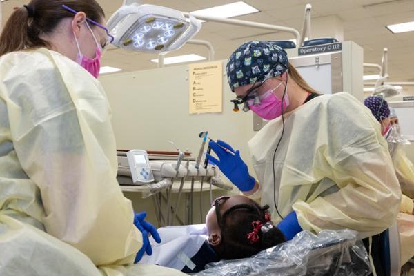 Students receive dental care and patient education at the SIU SDM clinic and gym during Give Kids A Smile Day (GKAS), SIU SDM first year Emily Bone plays tooth fairy to student at GKAS 