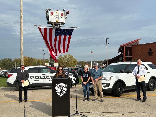 Mayor Tom Stalcup, Police Chief Brad Wells and Tyler Timmins's parents look on as Tyler's wife Linsey Timmins addresses the crowd.