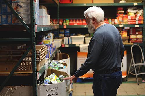 Warehouse Director Les Hahn, who has been a volunteer for five years, gives a tour of the center's food pantry. He said the firm's donation of food will help them easily get through the holidays and ensure area families have the food they need.