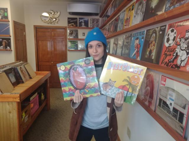 Becca Peterson, owner of Score! Records poses with two very beachy records, which may be in play tonight at Old Bakery Beer Company