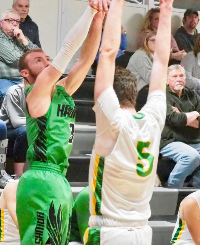 Carrollton junior point guard Ethan Brannan fires a three-point shot while Brown County's Camden Schmitz attempts to block the shot in the Winchester Invitational Tournament.
