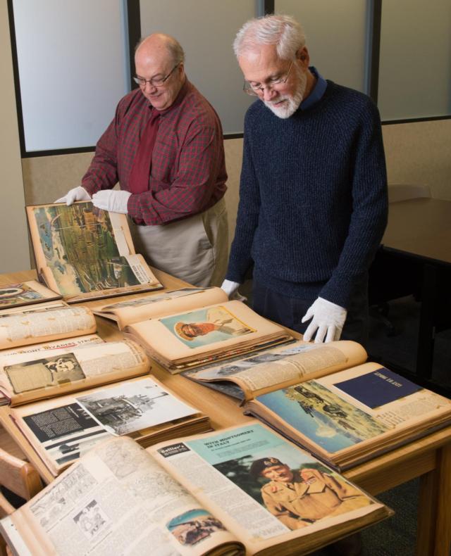University Archivist and Special Collections Librarian Stephen Kerber, PhD, (front) and LIS History Subject Liaison Matt Paris (back) carefully view the extensive set of scrapbooks dating from the 1940s which have been donated to SIUE&rsquo;s Library and Information Services. 
