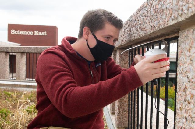 After retrieving data, SIUE environmental sciences graduate student Josh Gifford reinstalls a noise sensor on the Science West Green Roof.