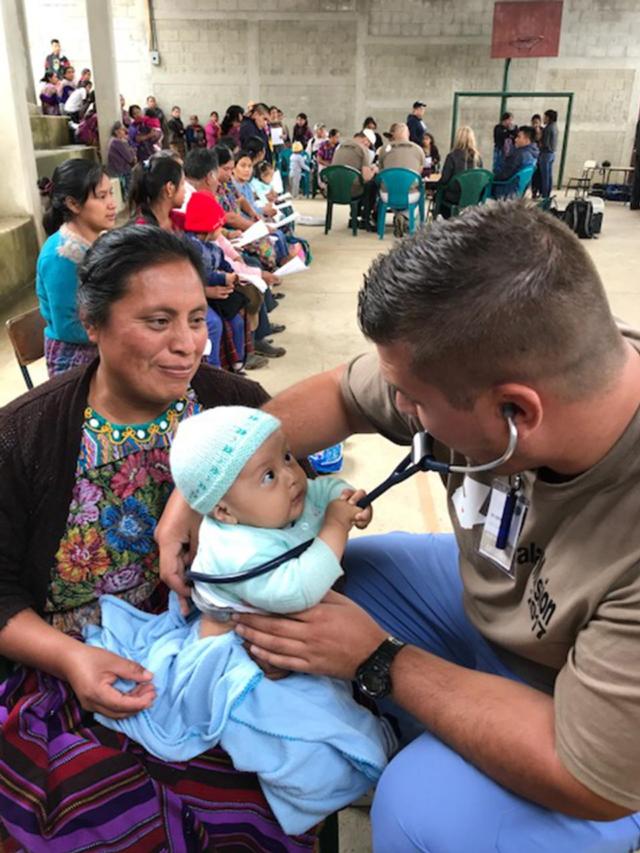 SIUE School of Nursing student Greg Jennings provides care for a baby in Guatemala.