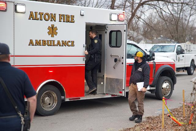 Officer talks to victim in ambulance as animal control officer looks on.