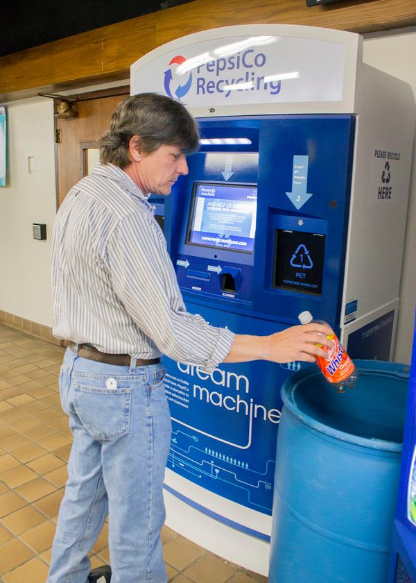 L&C Sustainability Club member and Army Veteran Max Parks recycles a plastic bottle in the blue barrel near L&C&rsquo;s Dream Machine. Those who want to recycle and support disabled veterans can now toss their can or bottle in the barrel, and the L&C Veterans Club will take care of the rest.