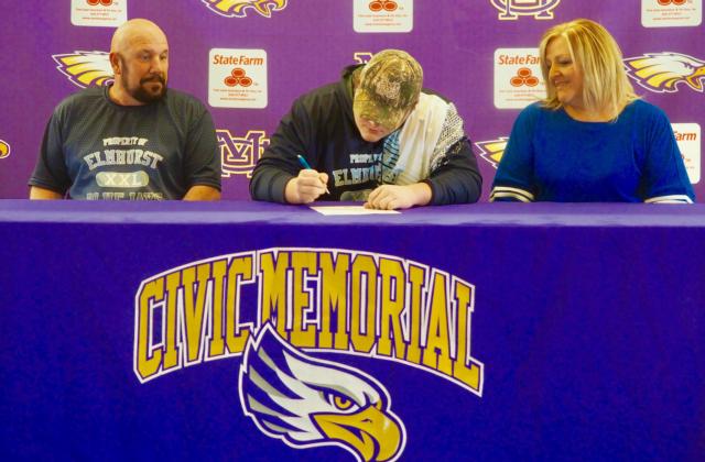 Wallace signs his letter of intent alongside his parents.