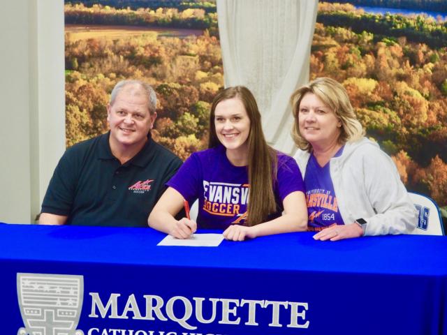Lauren Fischer sits alongside her parents after she signed her letter of intent to continue her academic and athletic career at the University of Evansville at Marquette Catholic High School on Thursday afternoon.