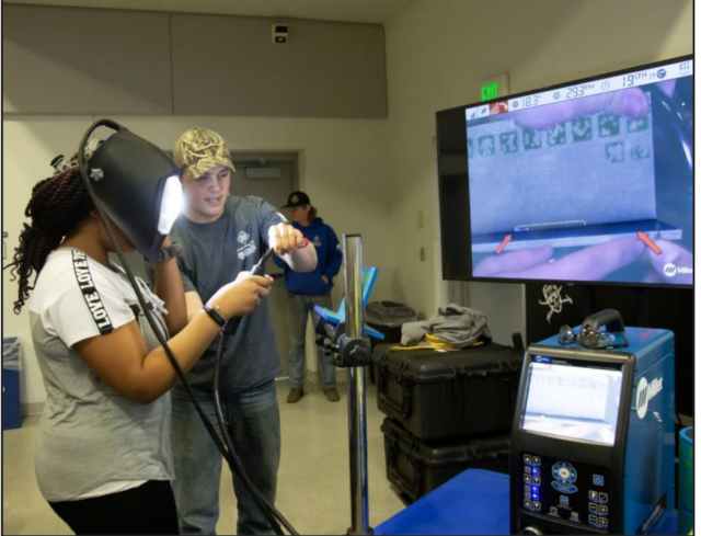 Second year Welding Technology student Adam Boeck guides prospective student, A’myiah Pittman, of Alton, through her first time using a welding simulator.