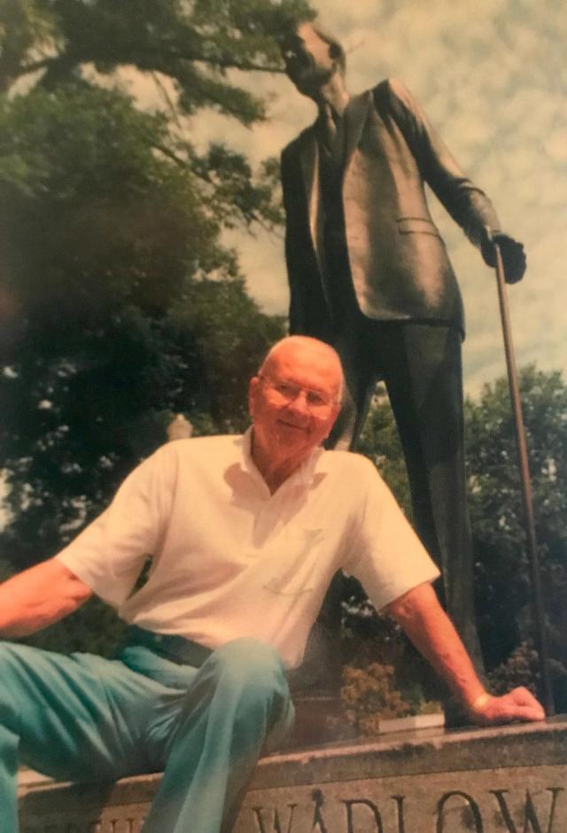 Harold Wadlow Jr. sits next to the statue of his famous brother, Robert.