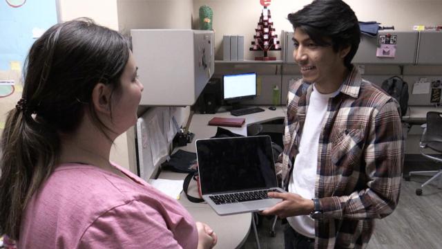 Tech Fusion co-owner Diego Espinoza picks up a computer from a student customer.