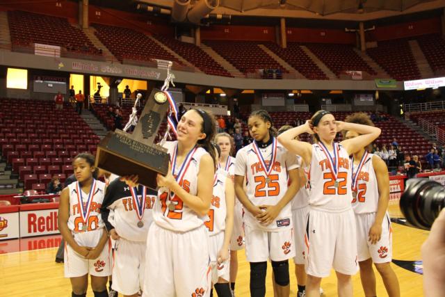 Makenzie Silvey raises up the second-place IHSA Class 4A state girls basketball trophy for her team. (Photo by Madelaine Gerard)