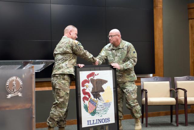 Lt. Col. Corey Wise of Bryant, Illinois, commander of Bilateral Embedded Support Team A-19, presents Maj. Gen. Michael Zerbonia of Chatham, Illinois, Assistant Adjutant General &ndash; Army, Illinois National Guard, with the Illinois flag the team flew on Bagram Air Base, Afghanistan. The team returned from Afghanistan in December and held a 90-day reintegration event March 3 at the Illinois Military Academy in Springfield, Illinois. (U.S. Army Photo by Sgt. 1st Class Bryan Spreitzer, Illinois National Guard Public Affairs)