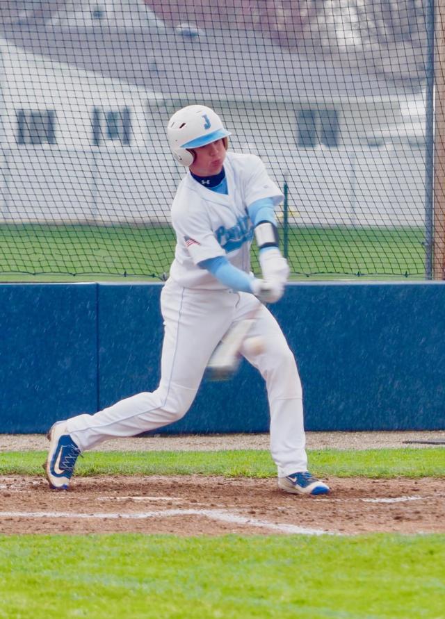 Jersey catcher, John Collins makes contact with the baseball in the rain against Rock Falls this past Saturday afternoon.