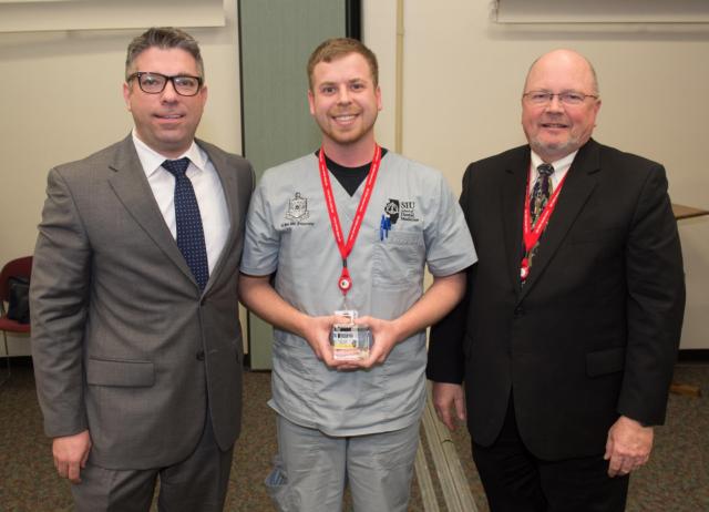 Joshua Gremillion with Dentsply (L) presented the Table Clinic Competition’s first place award to SIU SDM second year student Coleman Choate (middle), with Dean Bruce Rotter, DMD, (R) standing alongside.
