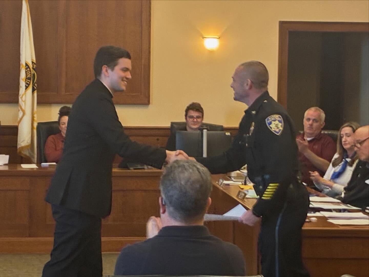 Father Garron Daniels (left) and Alton Police Chief Jarrett Ford (right) shake hands shortly after Daniels takes the oath as the department's newest chaplain.