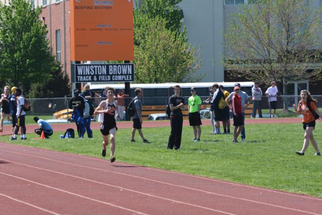Max Hartmann en route to his first place in the 3,200 meters. Julianna Determan, far right, a girls track star, encourages Hartmann on to the win.(Photo by Dan Brannan)