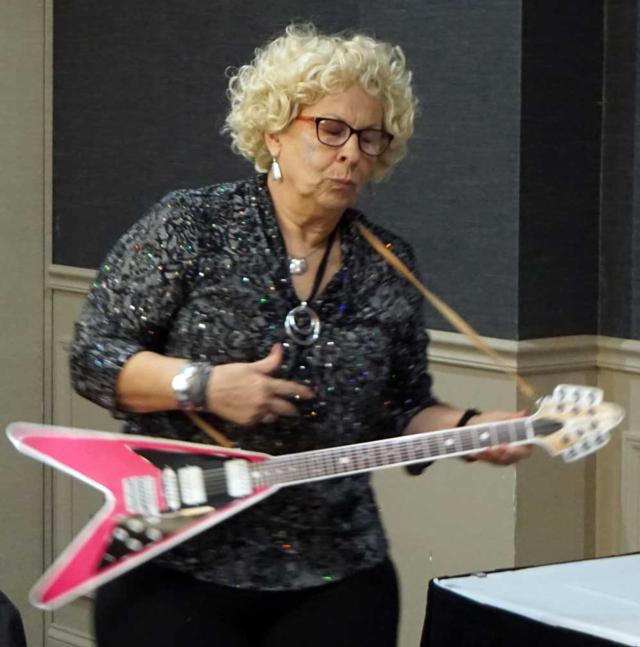 Volunteer Mary Eckhouse helped move things along at the luncheon, somewhere between air guitar and real guitar.