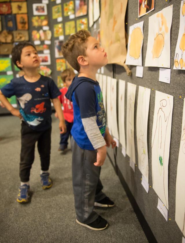 A student from the SIUE Early Childhood Center stands intrigued by his friends&rsquo; artistic creations.