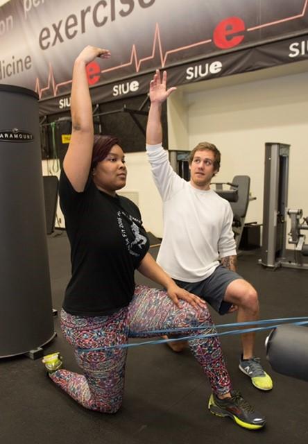 SIUE senior Cody Snyder, a native of Shelbyville, leads a participant in stretches during one of this project team&rsquo;s training sessions.