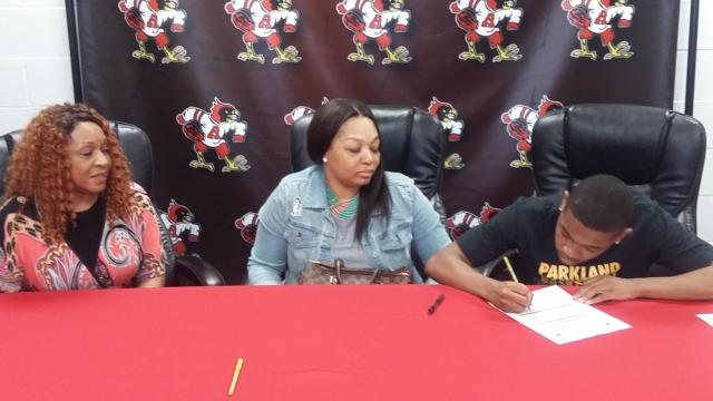 From left, Kimberly Taylor (grandmother), LaShaunte Taylor (mom) and Ty'Ohn Trimble signing with Parkland