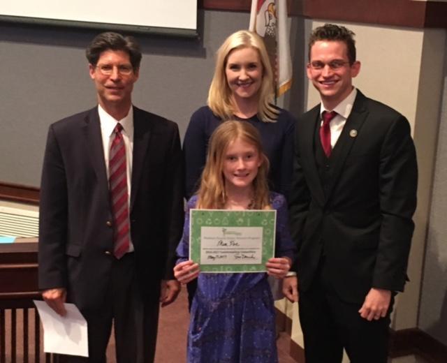 Prenzler, Drueke and County Board member David Michael present Mia Poe of St. Jacob Elementary School with a certificate of recognition for the Trashformation competition.