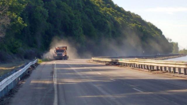 IDOT workers work to clear the mud and debris from the Great River Road on Monday morning. (Photo by Pat Schwarte).