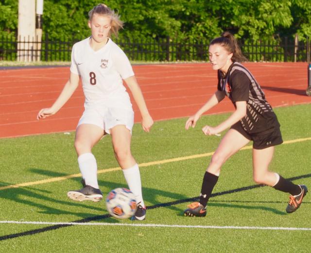 Raegan Grawe passing the ball while being marked by Edwardsville's Emma Hensley.