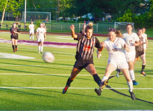 Belleville West's Courtney Vollmer (19) knocks the ball out of play before Edwardsville's Megan Woll (10) can get to it first.