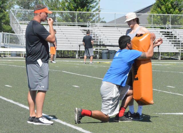 Coach Matt Martin and football star A.J. Epenesa demonstrate during a drill in the football camp at Edwardsville High School this week.