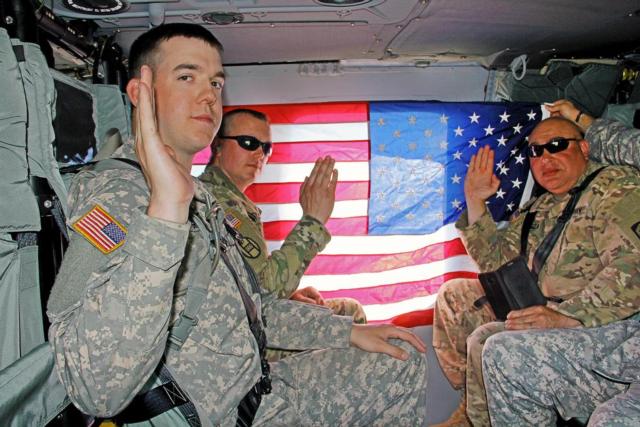 Sgt. 1st Class Corey Ginger of Rockford, Illinois, Staff Sgt. Chris Garza of Chicago, and Spc. Jacob Gray of Pontiac, Illinois, all with the 404th Maneuver Enhancement Brigade based in Normal, Illinois, raise their right hand in the air while on a helicopter with the American flag in the background, during annual training at Volk Field, Wisconsin, June 7. (U.S. Army photo by Staff Sgt. Aleah Castrejon, Public Affairs)