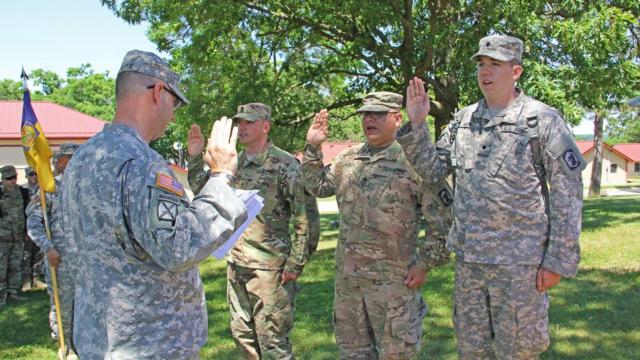 Capt. Timothy McDuffie of Bethalto, Illinois, the company commander of the Headquarters and Headquarters Company, 404th Maneuver Enhancement Brigade, reads the oath of enlistment while the Soldiers raise their right hand; (left) Sgt. 1st Class Corey Ginger of Rockford, Illinois; (center) Staff Sgt. Chris Garza of Chicago; and (right) Spc. Jacob Gray of Pontiac, Illinois all with the 404th MEB based in Normal, Illinois, re-enlist while in Volk Field, Wisconsin at annual training, June 7. (U.S. Army photo by Staff Sgt. Aleah Castrejon, Public Affairs)