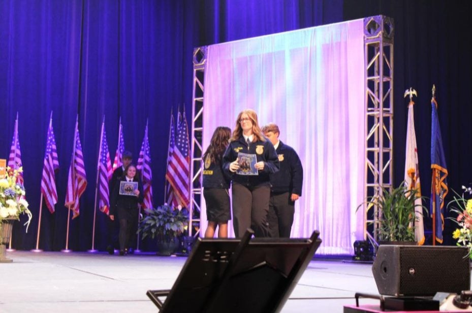 Chapter President Lucy Heepke walks the stage followed by Vice President Dylan Henke to accept Edwardsville FFA’s award as a Silver Chapter.