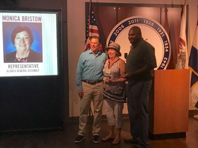 State Rep. Monica Bristow, D-Godfrey (center), alongside Senate sponsor State Sen. Elgie R Sims (right), is presented with the Champion Award.