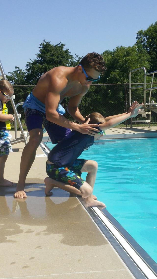 Cameron Essner, age 7, receives diving instructions from Nick Reynolds during a private lesson, while his younger brother, Gavin Essner, age 4, waits patiently for his turn.