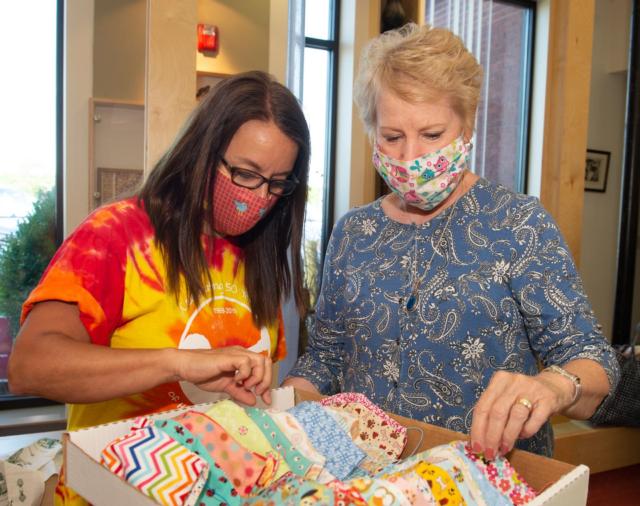 (L-R) SIUE ECC teacher Stephanie Henschen looks through some of the masks longtime ECC friend and retired Edwardsville teacher Kathy Weber made for ECC staff.