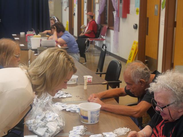 While visiting Beverly Farm&rsquo;s Community Day Services Center, State Senator Erica Harriss speaks with Beverly Farm residents who are working on assembling key chains.