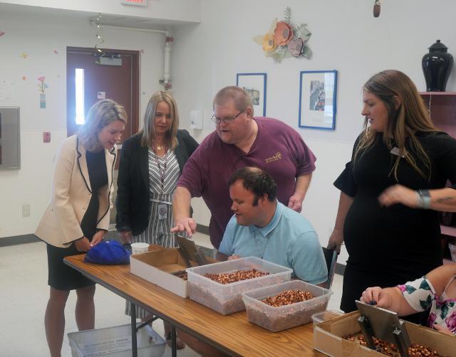 State Senator Erica Harriss and District Director for the 56th District Trina Vetter watch Beverly Farm residents performing a quality test on metal fittings during the Senator&rsquo;s visit to the Beverly Farm Community Day Services Center.