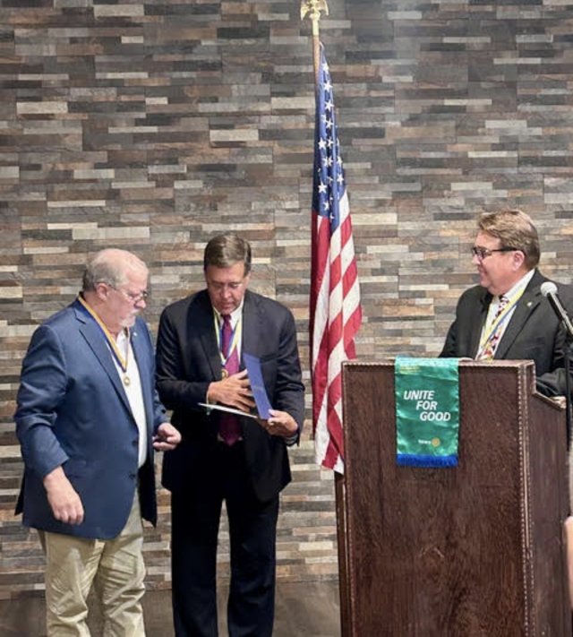 John Rain looks on as Steve Thompson presents the Paul Harris Fellowship Certificate to Mike Bates in recognition of his notable service to Alton Godfrey Rotary.