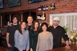 The Lorton family smiles behind the Nashville-style wooden bar.