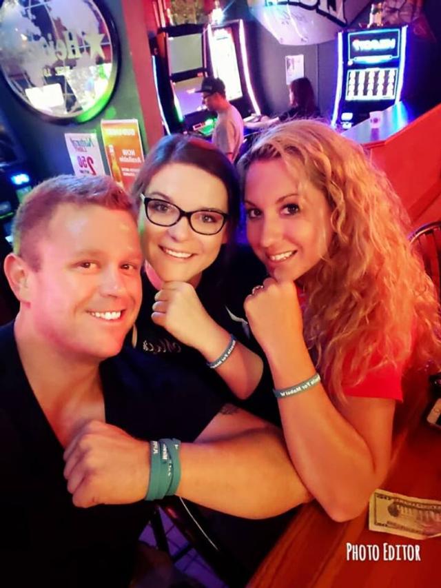 Sam Plunkett poses with two women wearing bracelets made for the event.
