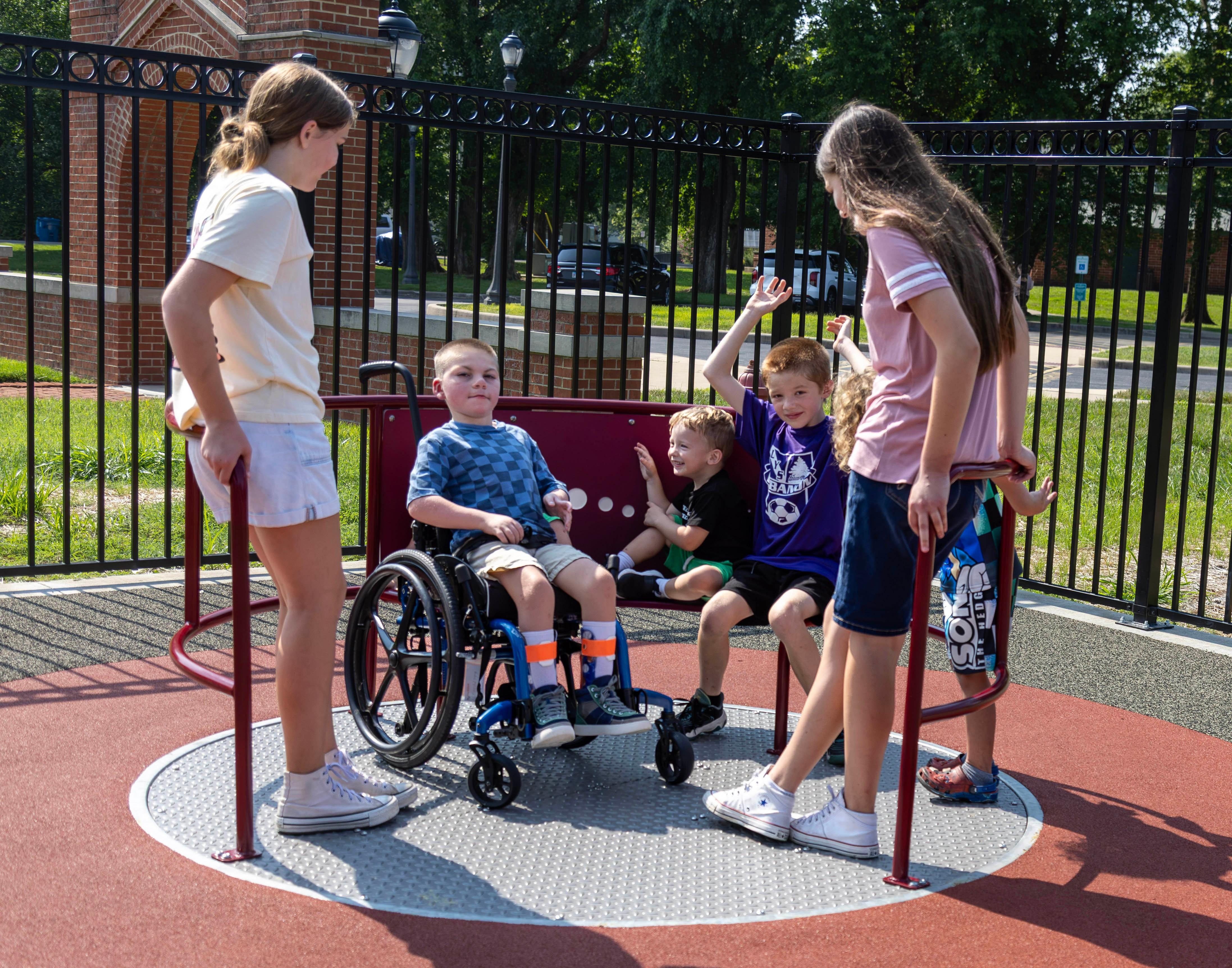 Henry Dunn (wheelchair) enjoys a ride on the accessible merry-go-round with his sisters Madison and Abbigail Dunn, and Luka and Dallas Goble.