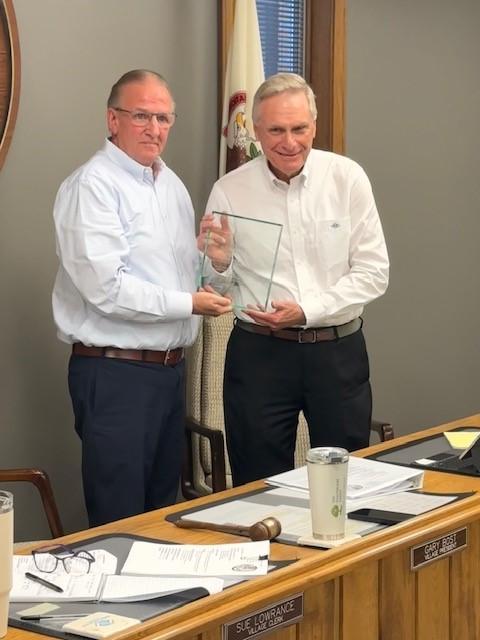 Mayor Gary Bost (left) presents longtime Village Attorney Ken Balsters (right) with a plaque commemorating his 42 years of service with the village.