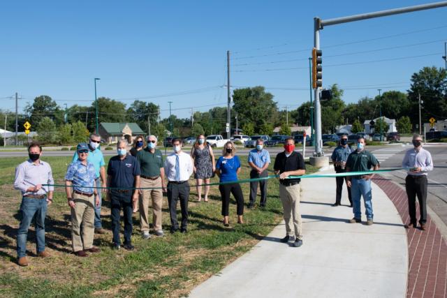  With the MCT Troy Park & Ride Lot in the background, MCT Board Members and staff, along with officials from the City of Troy, cut a ribbon for the new MCT sidewalk, which runs from US 40 to Turtle Creek along Troy-O’Fallon Road in Troy (Left to Right): Tom Cissell, Oates & Associates; MCT Board Chairman Ron Jedda; John Kramper, Hanks Excavating the project’s General Contractor; MCT Director of Engineering Mark Steyer; MCT Past Managing Director Jerry Kane; Madison County Board Chairman Kurt Prenzler; Stephanie Muentnich of Volkert & Associates; Michelle Ward of Anderson Hospital; MCT Director of Planning & Capital Projects Phil Roggio; Troy Mayor and MCT Board Member Allen Adomite; Troy Chief of Police Brad Parsons; MCT Assistant Project Manager Jon Martin; and MCT Managing Director SJ Morrison. 