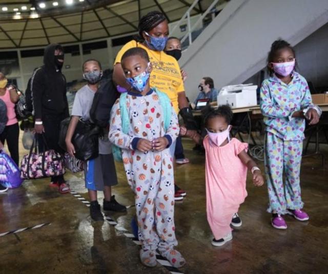 A family waits to board a bus to depart from the Lake Charles, La., area, where Hurricane Laura is expected to reach land on Thursday morning. (Associated Press photo)